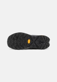 Talpă din cauciuc negru cu caneluri și crestături adânci pentru tracțiune, având un logo Vibram portocaliu proeminent. Finisaj texturat pentru durabilitate.