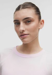 Top roz deschis cu dungi, cu guler rotund și material texturat. Prezentând o vedere de aproape care evidențiază culoarea delicată și pielea netedă.