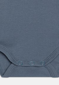 Ribbad mörkblå bodysuit med tre tryckknappar i botten, med en mjuk textur och rundad halsringning.