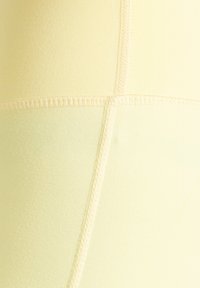 Gelbe nahtlose Leggings mit glatter Textur, Nahtdetails und elastischem Bund für Komfort und Flexibilität.