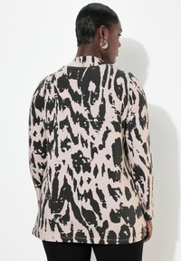 Langärmliges Shirt in Pink mit einem schwarzen, abstrakten Leopardenmuster. Es hat einen lockeren Schnitt und besteht aus einem weichen, glatten Stoff mit einem leicht abgerundeten Saum.
