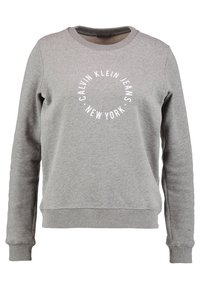 Sudadera de manga larga gris con cuello redondo, con puños y dobladillo acanalados, que presenta el texto blanco en forma de círculo "Calvin Klein Jeans New York" en la parte frontal.