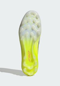 Σόλα παπουτσιού ποδοσφαίρου σε κίτρινο και λευκό, με υφή επιφάνειας που διαθέτει στρογγυλά καρφιά για πρόσφυση και λογότυπο "F50" σε ροζ.