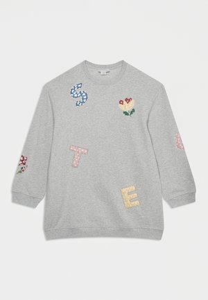 Chemise gris clair à manches longues avec des lettres brodées colorées "S," "T," et "E,", ainsi qu'un motif floral sur la poitrine et les manches.