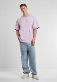 Light purple cotton t-shirt with short sleeves and round neckline, paired with loose-fitting light blue denim jeans and white sneakers.