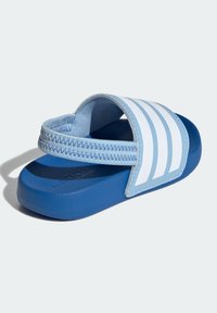 Blue slide sandals with a soft textured strap, featuring three white stripes and a sturdy blue rubber sole.