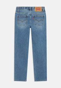 Jeans de mezclilla azul con corte recto, que cuentan con un parche de cuero en la pretina y dos bolsillos traseros con costuras distintivas.