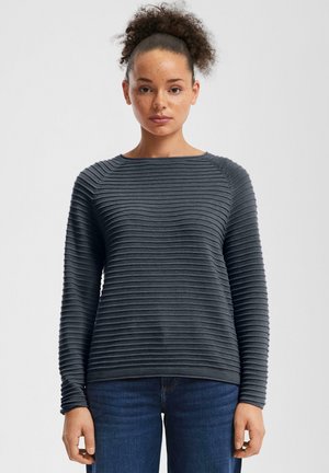 Grijze gebreide trui met horizontaal geribd patroon, ronde halslijn en lange mouwen, gecombineerd met blauwe jeans. Strakke pasvorm.