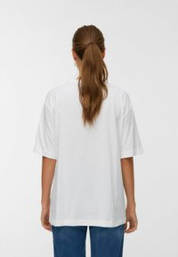 Witte oversized t-shirt met een ontspannen pasvorm en korte mouwen, gemaakt van zachte katoen. De achterkant heeft een eenvoudig ronde halsontwerp.