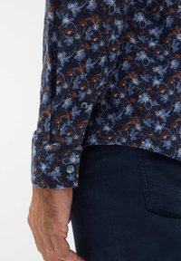 Katoenen langemouwen shirt met een donkerblauw bloemenpatroon, voorzien van lichtblauwe en bruine accenten; enkele knoop manchetten; gestructureerde stof.