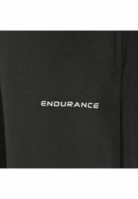 Svarta träningsbyxor i mjukt tyg, med en vit "ENDURANCE"-logotyp på vänster sida, med en slät textur och elastisk midja.