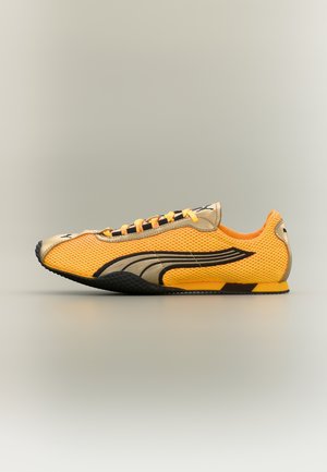 Žltá a béžová športová obuv z sieťoviny s čiernym a béžovým logom Puma, čiernou podrážkou a žltými šnúrkami na neutrálom pozadí.