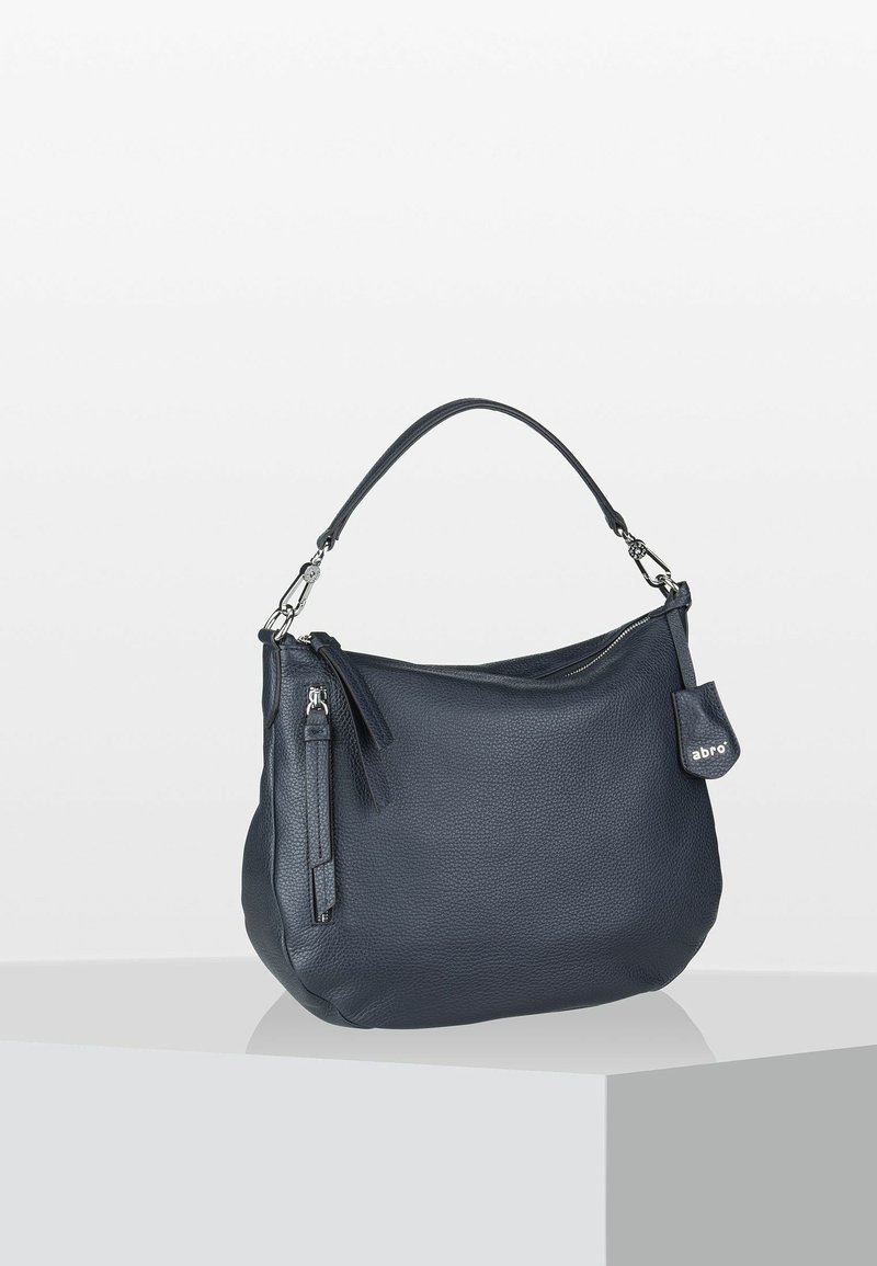 Sac à main en cuir bleu marine avec une surface texturée, une poignée courte et une poche zippée supplémentaire. Présente un accent avec une étiquette de marque.