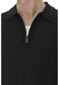 Polo negro de punto con textura acanalada, cuello con cremallera y un suave y cómodo acabado, diseñado para una silueta ajustada. La capa interior se muestra blanca.