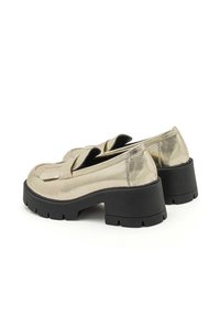 Metallieke goudkleurige loafers met een stevige zwarte rubberen zool, voorzien van een verhoogde franjerand en een soepele lederen textuur.