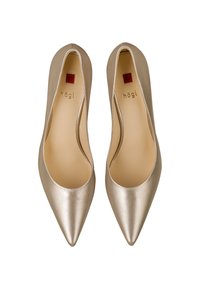 Escarpins métalliques dorés ponctués avec un bout pointu et des côtés ouverts. Texture lisse, tige en cuir et intérieur de marque.