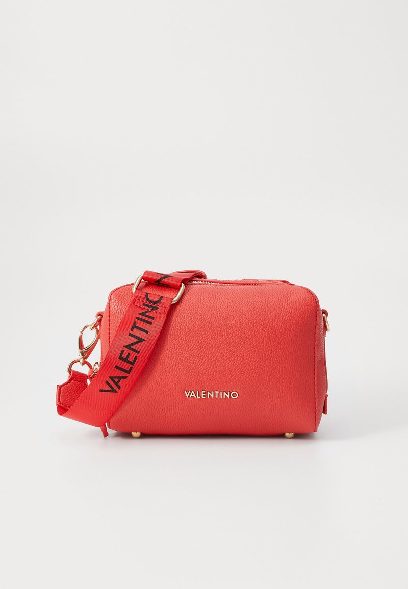 Červená kabelka z broušené kůže se zlatým kováním; má odnímatelný popruh s logem "VALENTINO" a horní zapínání na zip.