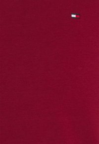 Red cotton T-shirt featuring a small embroidered logo in blue, white, and red, smooth texture, and classic fit.