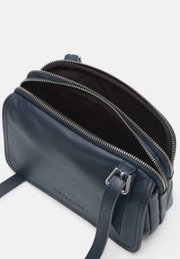Borsa a tracolla in pelle blu marino con tre scomparti con zip, texture liscia e hardware in tonalità argento. Inclusa una tracolla regolabile.