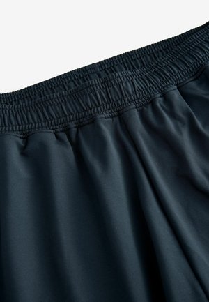 Tamsūs elastingi gymsai su švelnia, lygiomis tekstūromis ir laisva forma, su subtiliomis surinkimo detalėmis juosmens srityje.