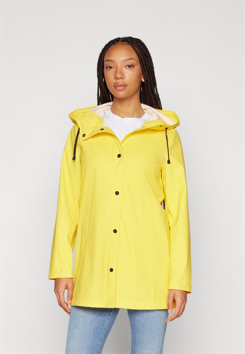 Yellow waterproof jacket with a hood, black buttons, and drawstring. Features two side pockets and a slightly relaxed fit.