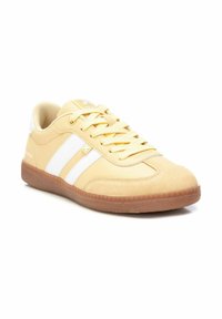 Zapatilla amarilla con franjas blancas, hecha de materiales sintéticos y de ante suaves, suela de goma, punta redonda y parte frontal con cordones. Mar branding sutil en el lateral.