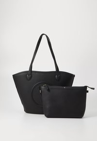 Sac fourre-tout en cuir noir avec une surface texturée, des poignées arrondies, et un petit pouch intérieur avec fermeture éclair. Les deux sacs sont élégants et minimalistes.