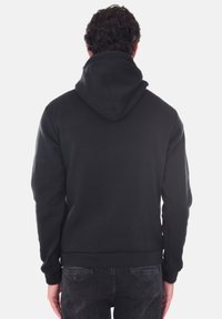 Felpa nera con cappuccio, caratterizzata da polsini e orlo a coste e una texture morbida. Mostrata dal retro, mette in risalto il design del cappuccio.