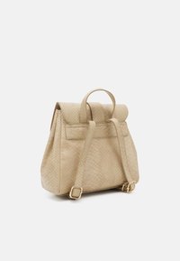 Mochila beige hecha de material texturizado con cierre enrollable en la parte superior, dos correas para los hombros y detalles en tono dorado.