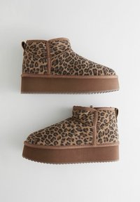 Kotníkové boty s leopardím potiskem, hnědý textilní svršek, pevná hnědá podrážka a poutko na zadní straně pro snadné obouvání.