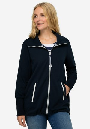 Giacca zip-up blu navy con colletto, zip bianca e due tasche frontali con dettagli bianchi. Tessuto morbido e vestibilità comoda.