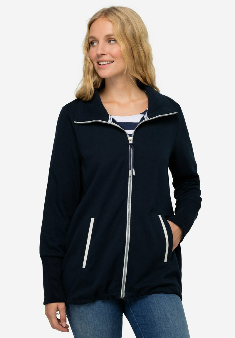 Giacca zip-up blu navy con colletto, zip bianca e due tasche frontali con dettagli bianchi. Tessuto morbido e vestibilità comoda.