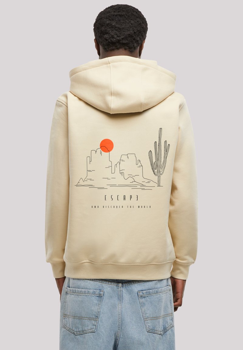 Beige hoodie featuring a graphic design of mountains, a sun, and a cactus on the back. Text reads "ESCAPE AND DISCOVER THE WORLD."