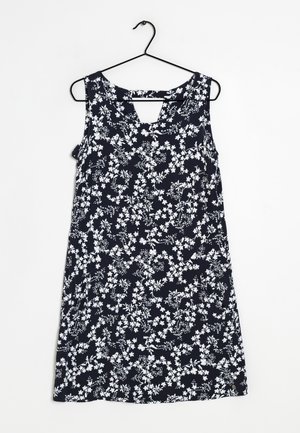 Vestito senza maniche blu navy con stampa floreale bianca e piccolo intaglio a V sullo scollo, appeso a una gruccia nera.