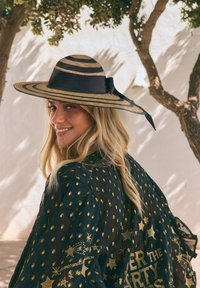 Stråhatt med bred brätte och växelvis svarta och naturfärgade ränder, med ett rosettbundet band. Svart kimono med mönster och detaljer i guldstjärnor.