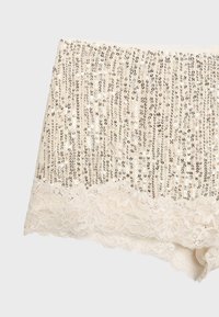 Shorts en dentelle beige ornés de sequins argentés verticaux sur tout le tissu, avec une bordure en dentelle florale à l'ourlet.