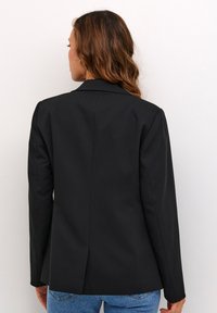 Černý blazer se strukturovaným designem, s klopami a jedním zadním rozventem. Tkanina vypadá hladce a má přizpůsobený střih.