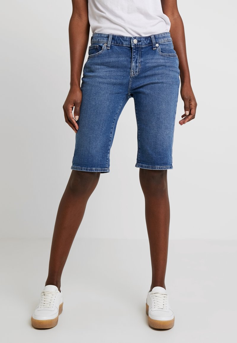 Denim bermuda korte broek in middelblauw. Voorzien van riemlussen, vijf zakken en een rechte pasvorm. Zoom afgewerkt met subtiele stikdetails.