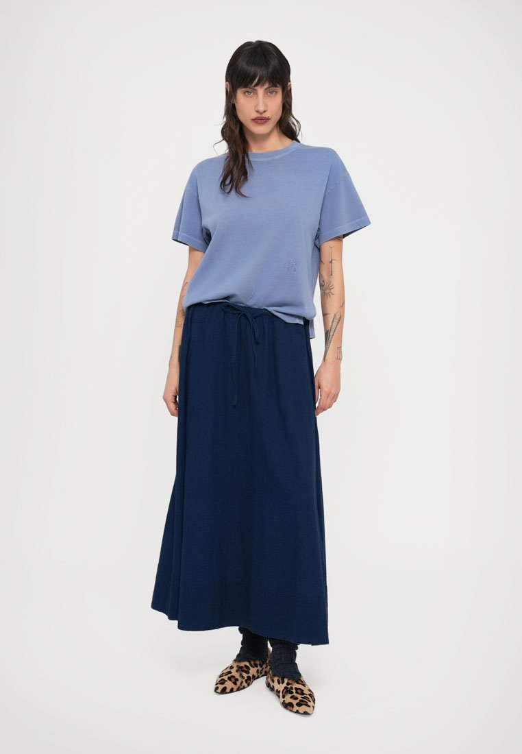 Chemise bleu clair à manches courtes, longue jupe bleu marine avec ceinture nouée à la taille, et chaussures à imprimé léopard. Tissu lisse avec une coupe décontractée et une silhouette fluide.