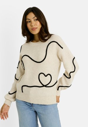 Suéter de punto crema con líneas texturizadas negras que forman formas abstractas y un motivo de corazón. Los puños y el dobladillo acanalados añaden detalle.