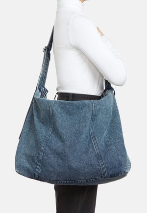 Jeanstasche mit breiter, weicher Form, hellblauer Farbe und kontrastierender Naht; inklusive langem, verstellbarem Tragegurt.