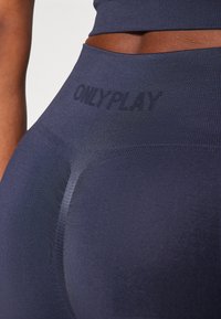 Marinefargede sømløse leggings med høy midje og subtil merkevare på toppen, med en jevn og elastisk tekstur.