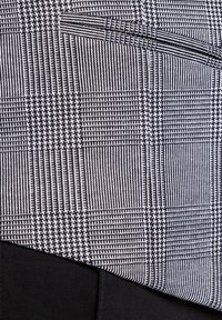 Czarny i biały materiał w wzory, z połączeniem deseniu houndstooth i pasków, o teksturowanej powierzchni. Gładki czarny materiał znajdujący się pod spodem.