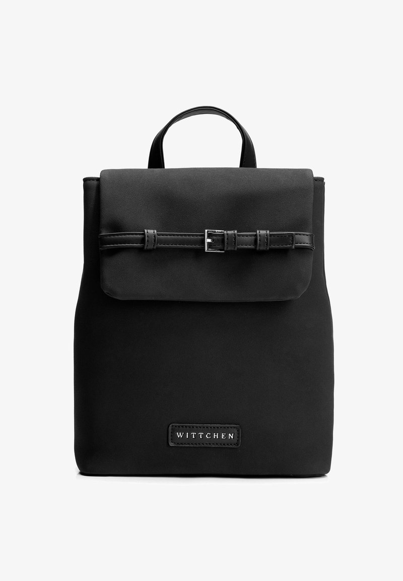 Černý obdélníkový batoh s klopou upevněnou tenkým páskem se sponou a horním uchem, na přední straně označený štítkem "WITTCHEN".