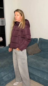 Bordó krāsas polsterēta jaka ar kapuci, ar priekšējo rāvējslēdzēju un priekšējo kabatu. Valkāta kopā ar gaiši pelēnām platām biksēm un baltām sporta kurpēm.