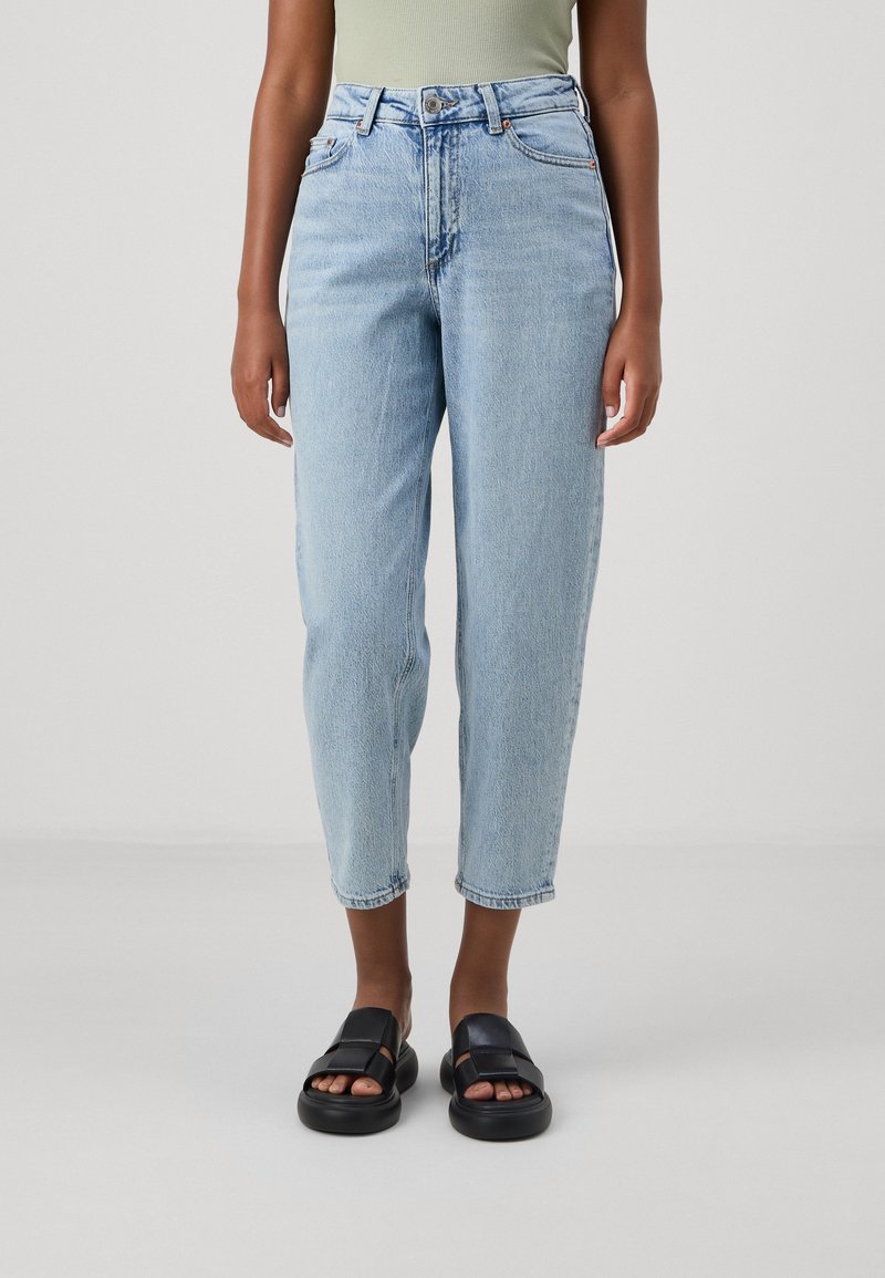 Helle blaue, hochtaillierte, lässige Jeans aus Denim mit Knopfverschluss, fünf Taschen und umsäumten Säumen. Kombiniert mit schwarzen Sandalen.