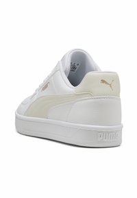 Baskets Puma blanches et beiges vues de l'arrière, montrant le logo sur le talon et sur le côté avec une semelle texturée.