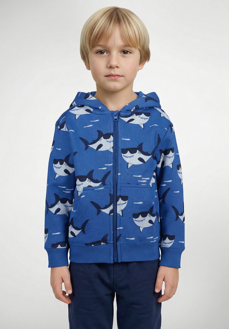 Sweat à capuche zippé bleu avec un motif de requins, présentant des requins gris et bleu marine portant des lunettes de soleil. Fabriqué en tissu doux avec une capuche et des poches avant.