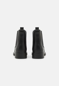 Bottines en cuir noir avec des panneaux latéraux élastiques, bout rond et petit talon carré. Comprend des languettes à l'arrière pour un enfilage facile.