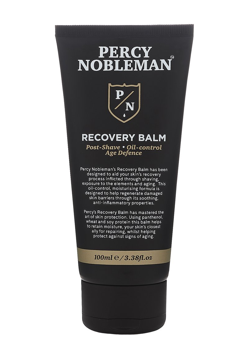 Zwarte tube met gouden accenten, voorzien van witte tekst. Inclusief een verzegelde dop en etiket met de tekst "Recovery Balm" en productdetails. Inhoud van 100 ml.